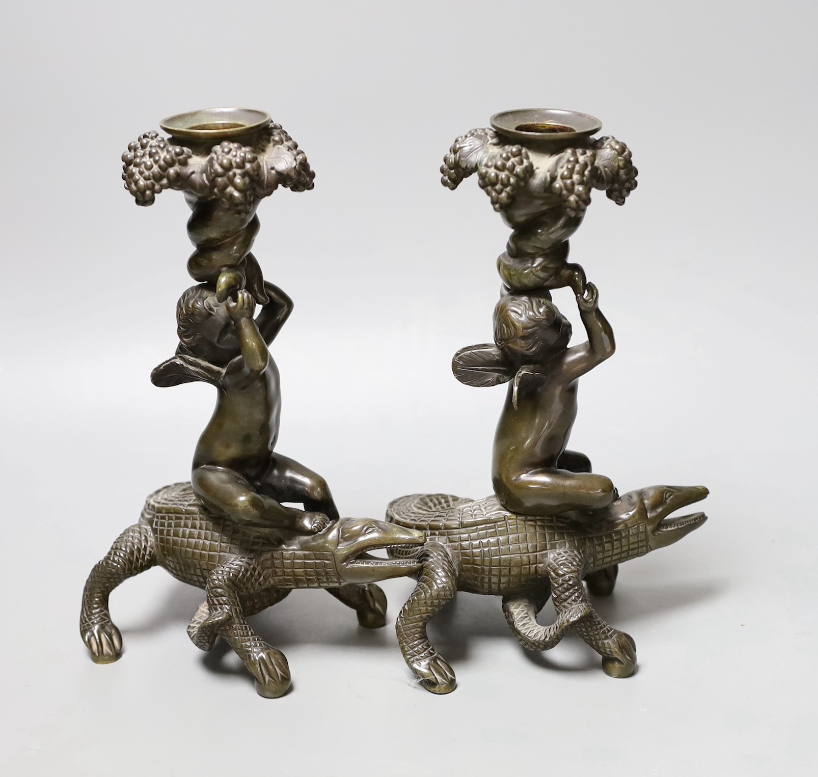 A pair of late 19th century bronze candlesticks modelled as cherubs riding crocodiles, 21.5cm